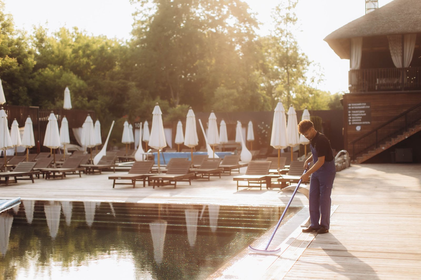 Pool cleaner skimming leaves at luxury hotel resort during sunrise