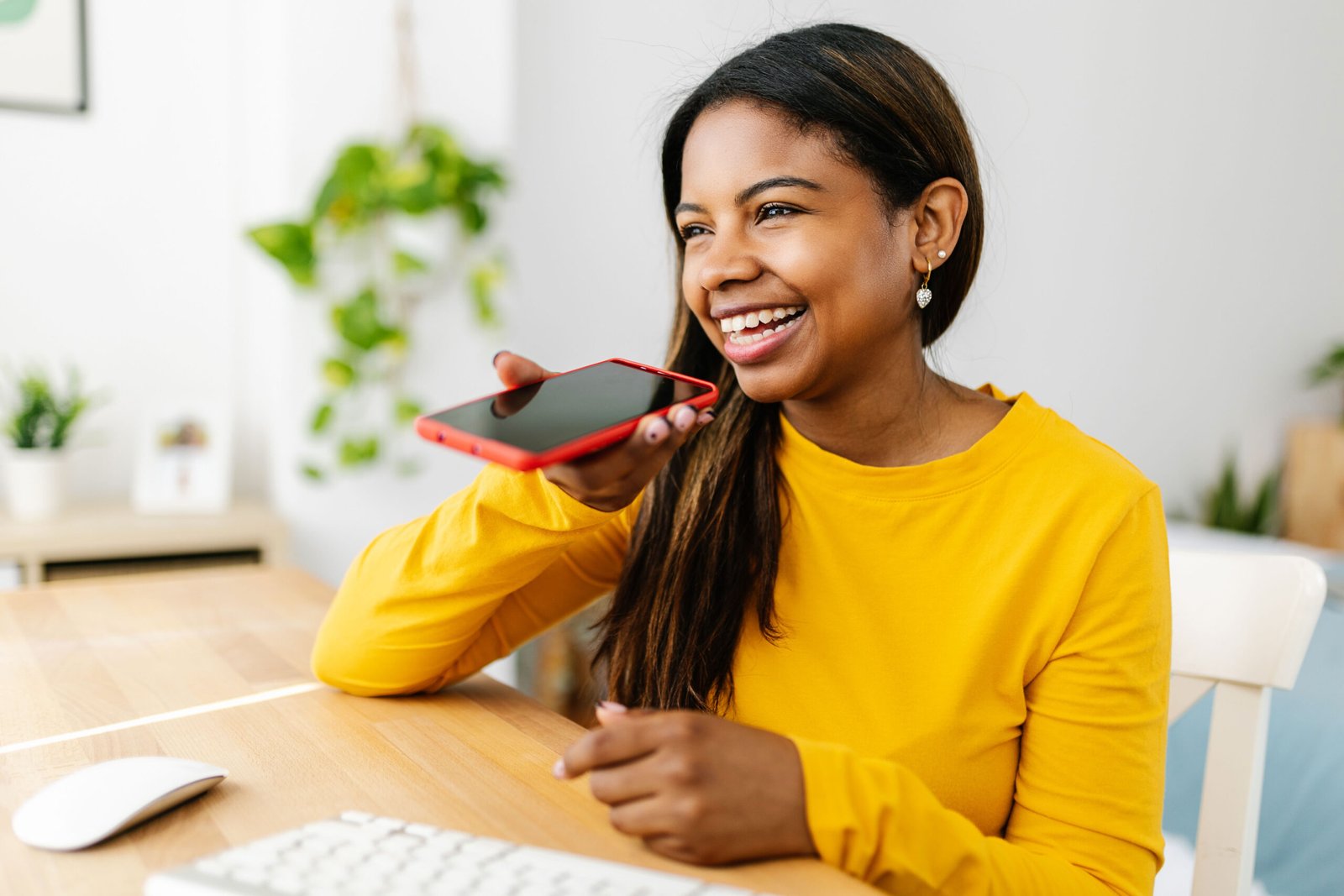 Happy ethnic young woman using mobile phone sitting at desk on r